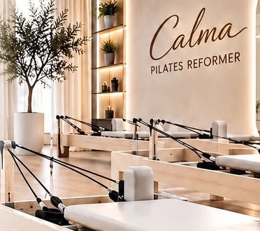 Залата на Calma с реформъри и надпис Calma Pilates Reformer на стената